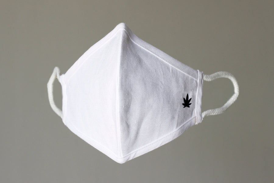 White hemp fabric face mask angled side view, contoured shape with black trim and soft ear loops