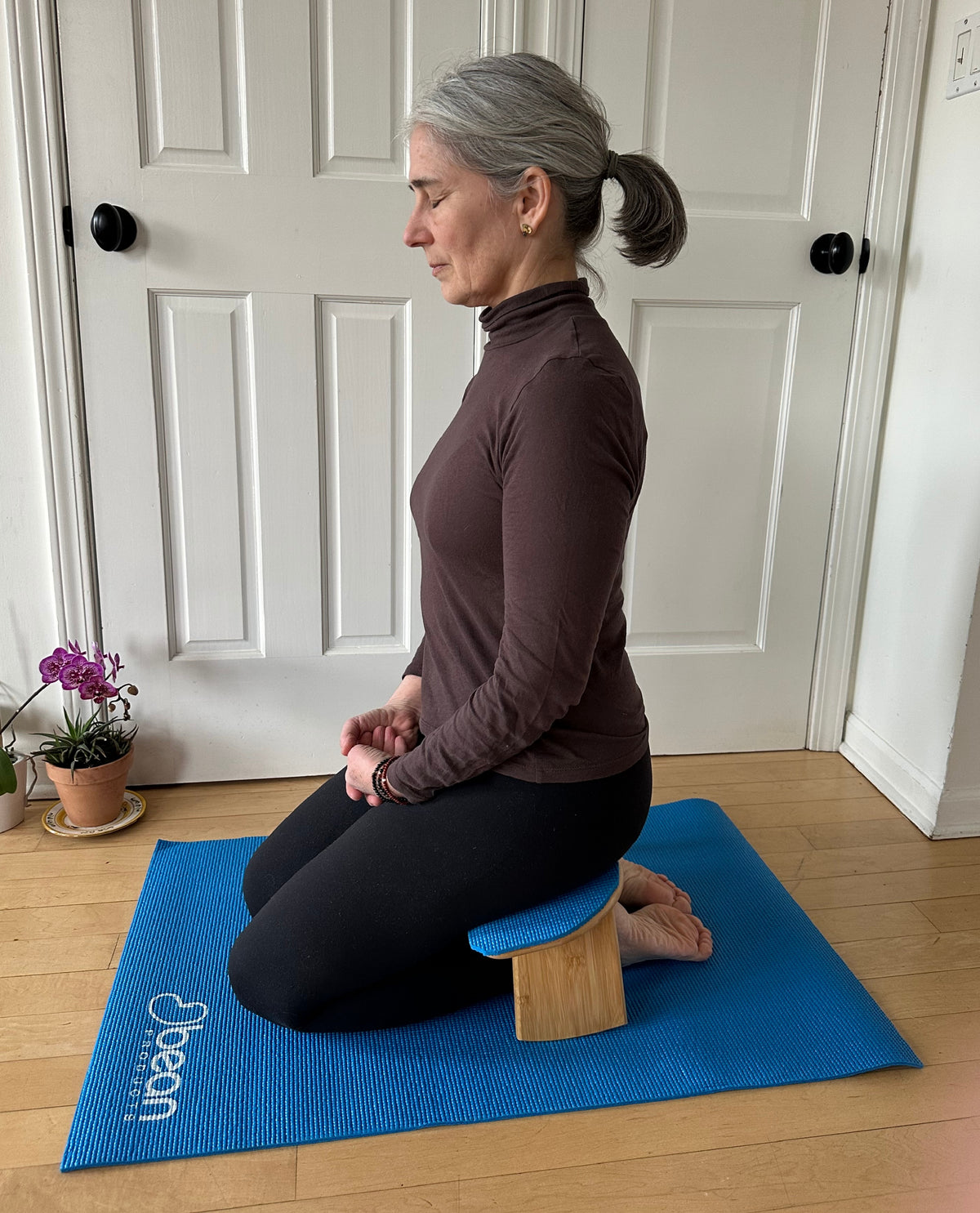 Woman sitting upright on bamboo meditation bench for posture support