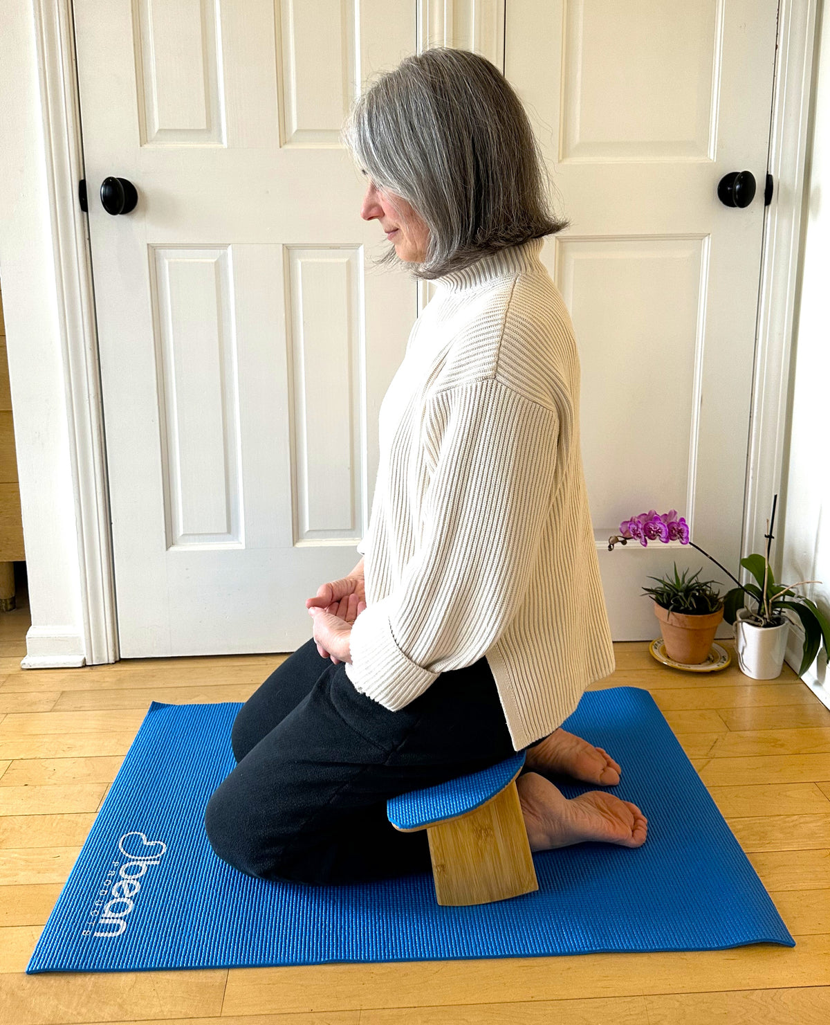 Woman using kneeling bench for prayer and meditation on yoga mat