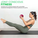 Woman exercising with a soft weighted resistance ball on a mat, promoting joint-conscious fitness.