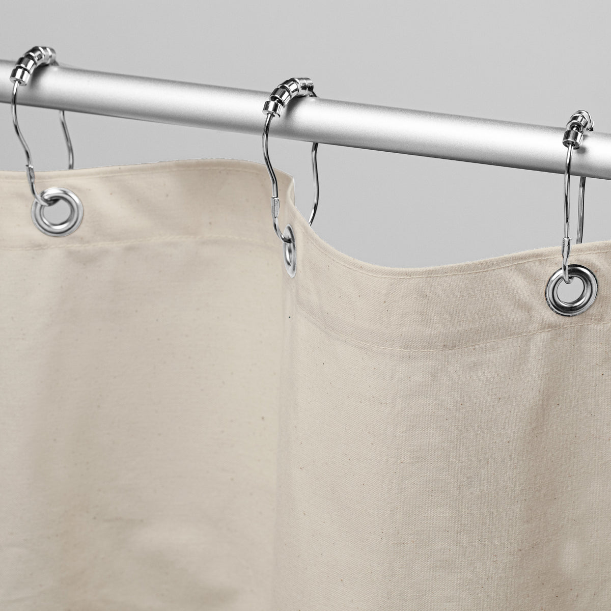 Beige organic cotton shower curtain hanging on chrome rod
