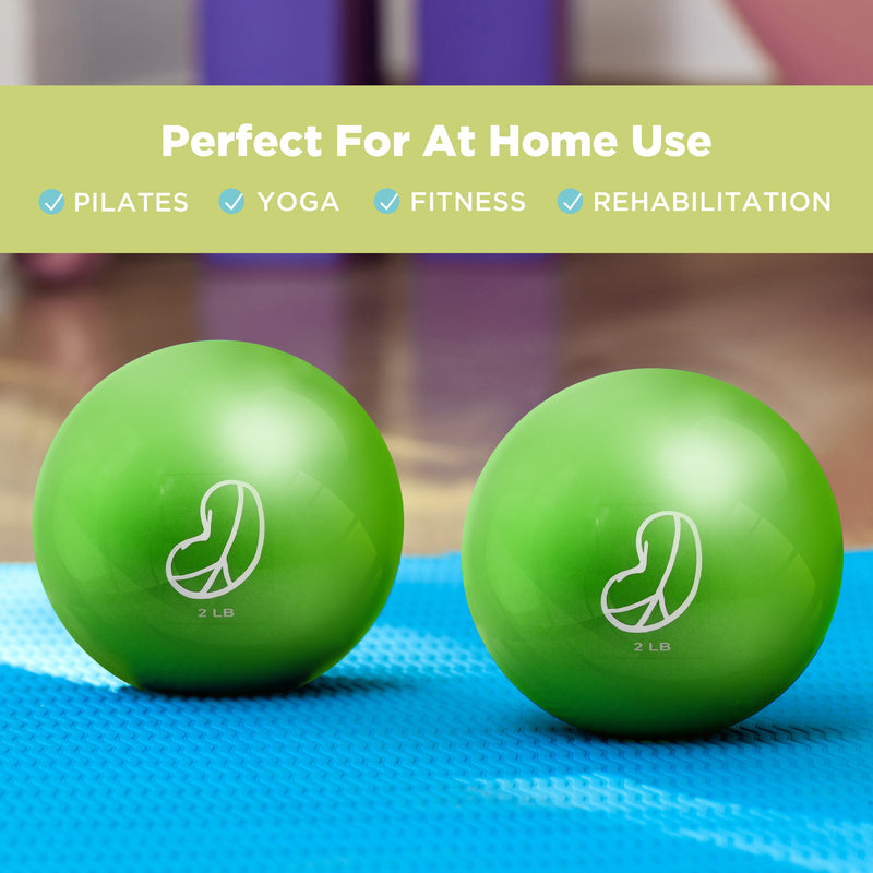 Two green soft weighted exercise toning balls on a blue mat with text indicating their use for Pilates, Yoga, Fitness, and Rehabilitation.