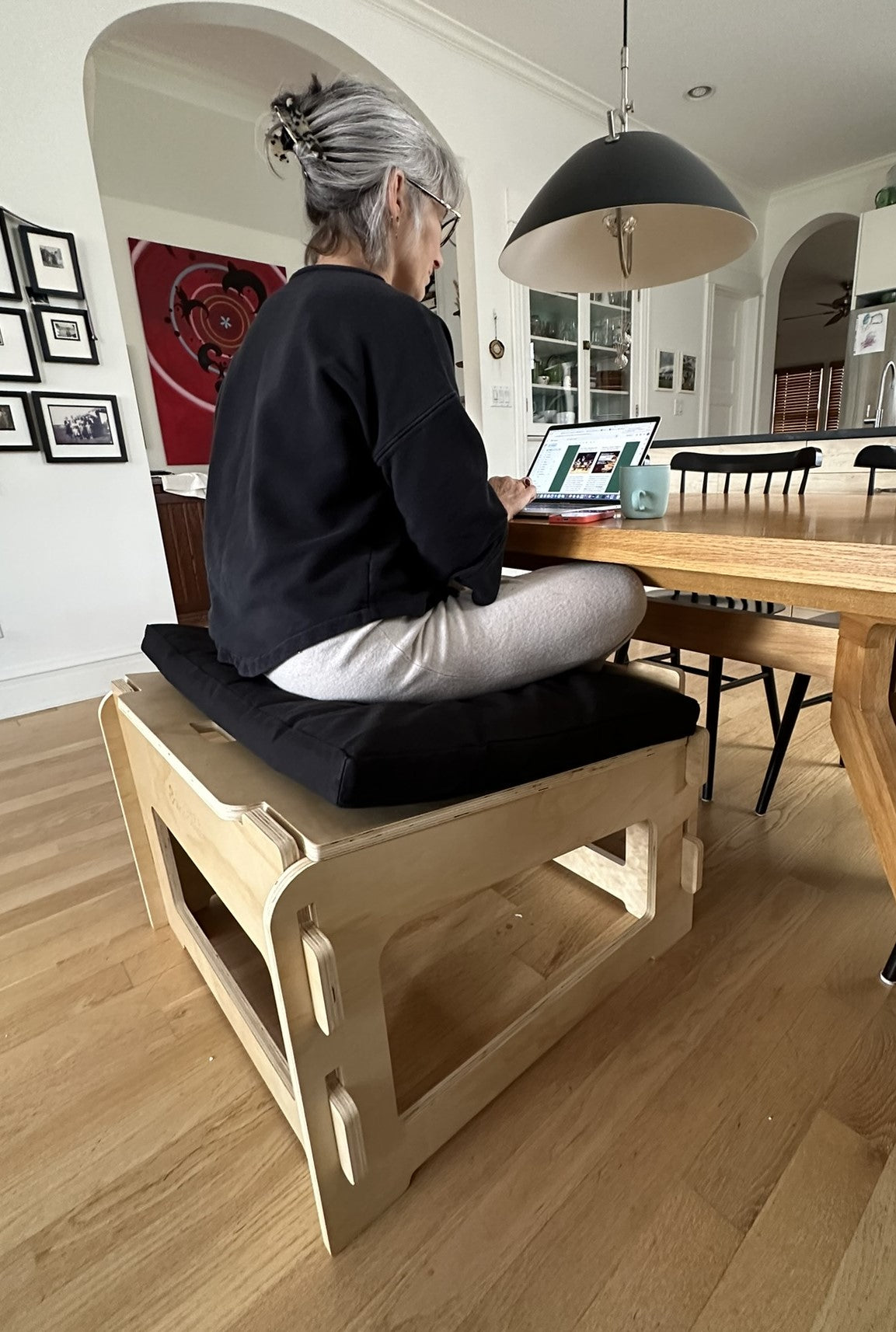 Person sitting on ergonomic meditation stool at desk workspace for active sitting posture