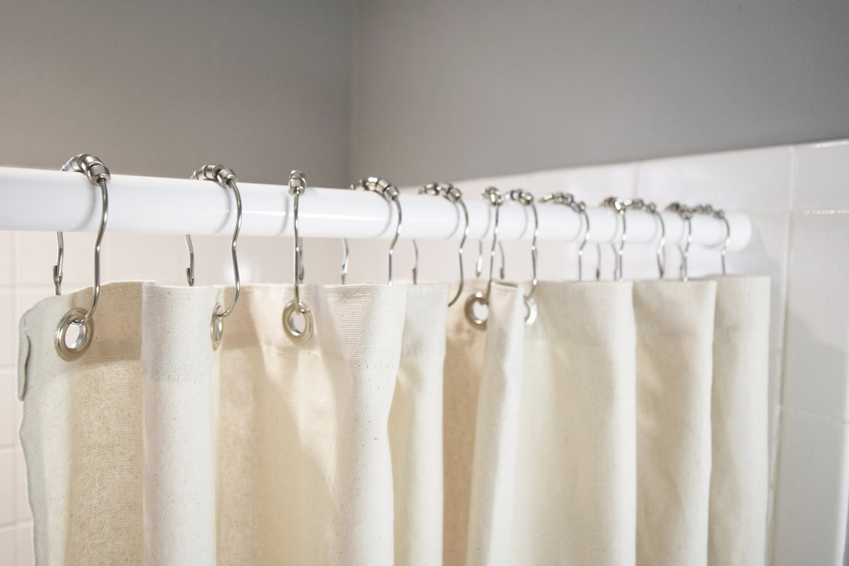 Beige organic cotton shower curtain hanging with white rings