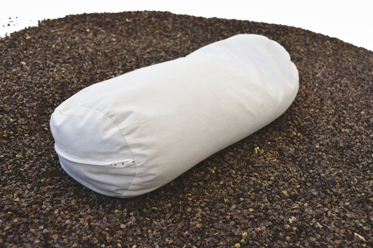 White neck roll pillow placed on dark gravel background showing firmness and shape