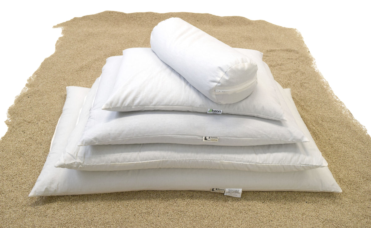 Folded white pillow covers stacked on natural millet hulls for organic pillow filling