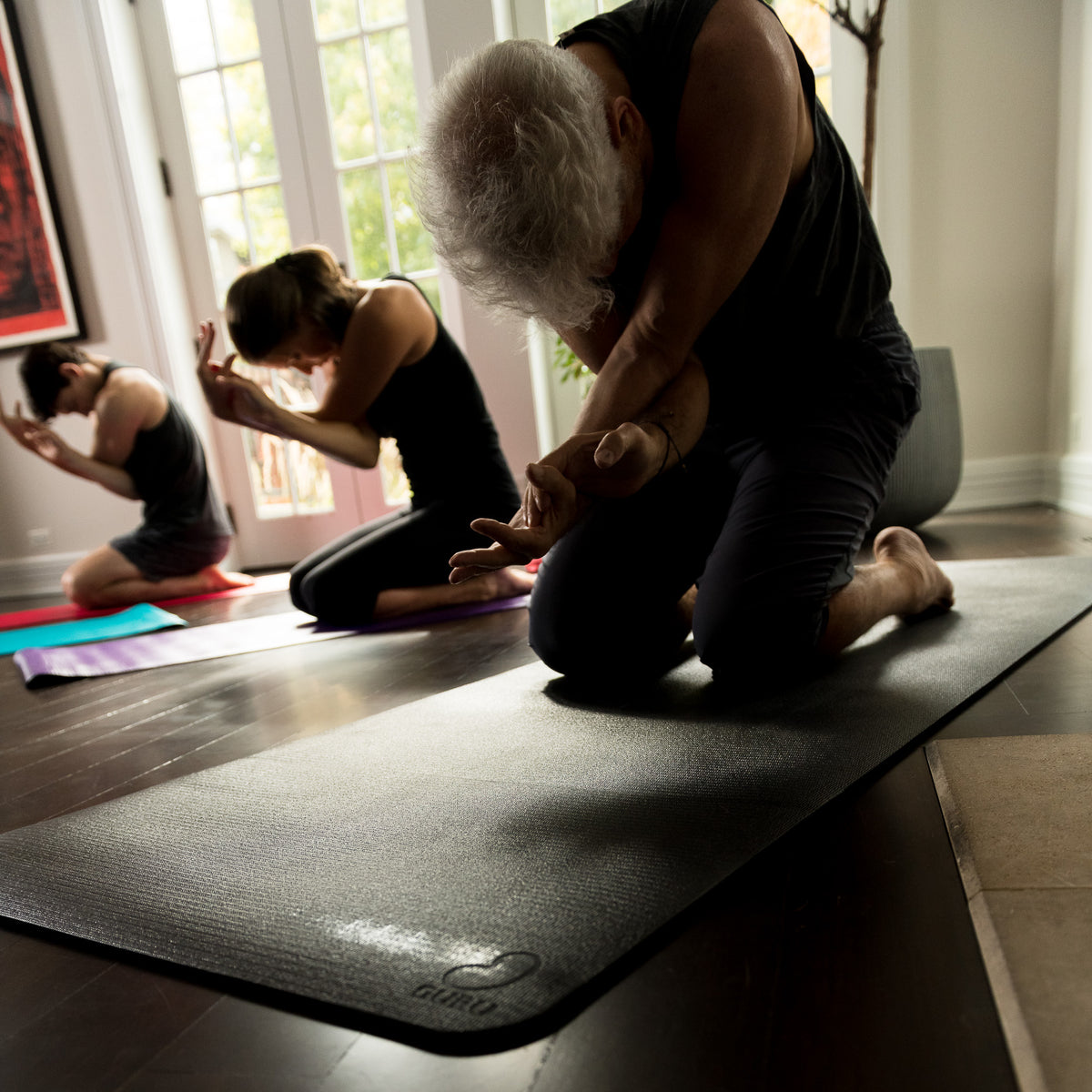 Person rolling black Pro Eco GURU Yogi yoga mat for storage