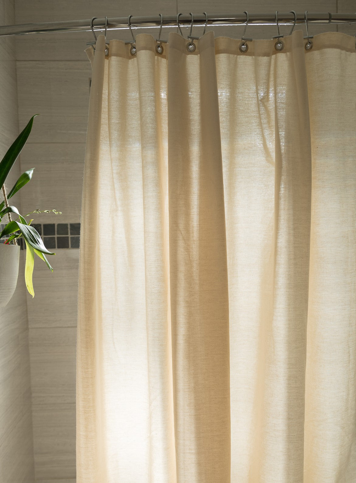 Natural cotton shower curtain installed in bright bathroom setting