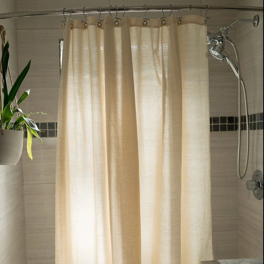 Natural cotton shower curtain in beige installed on bathtub with chrome rod, soft linen look fabric