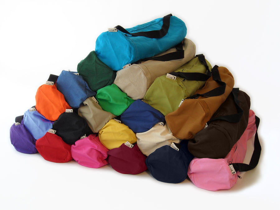 A collection of cotton yoga mat bags in various solid colors arranged together.