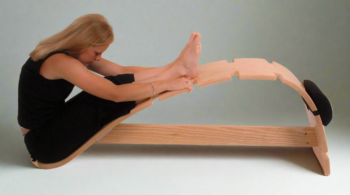 Woman stretching forward on whale bench, improving hamstring flexibility and posture alignment with back support