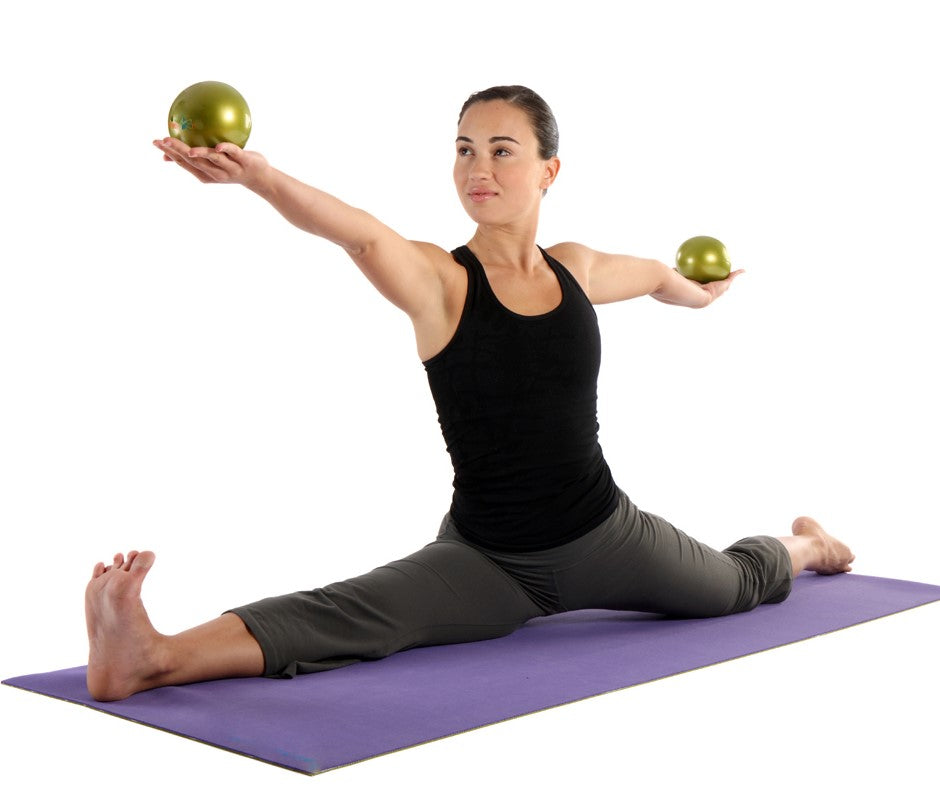 Yogini using 2 soft weighted balls in a split pose on a yoga mat