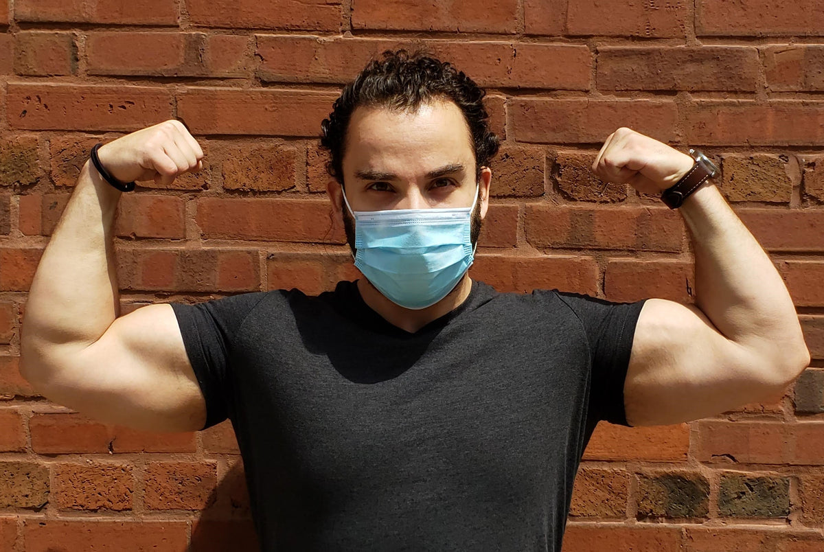 Man flexing arms while wearing disposable blue face mask