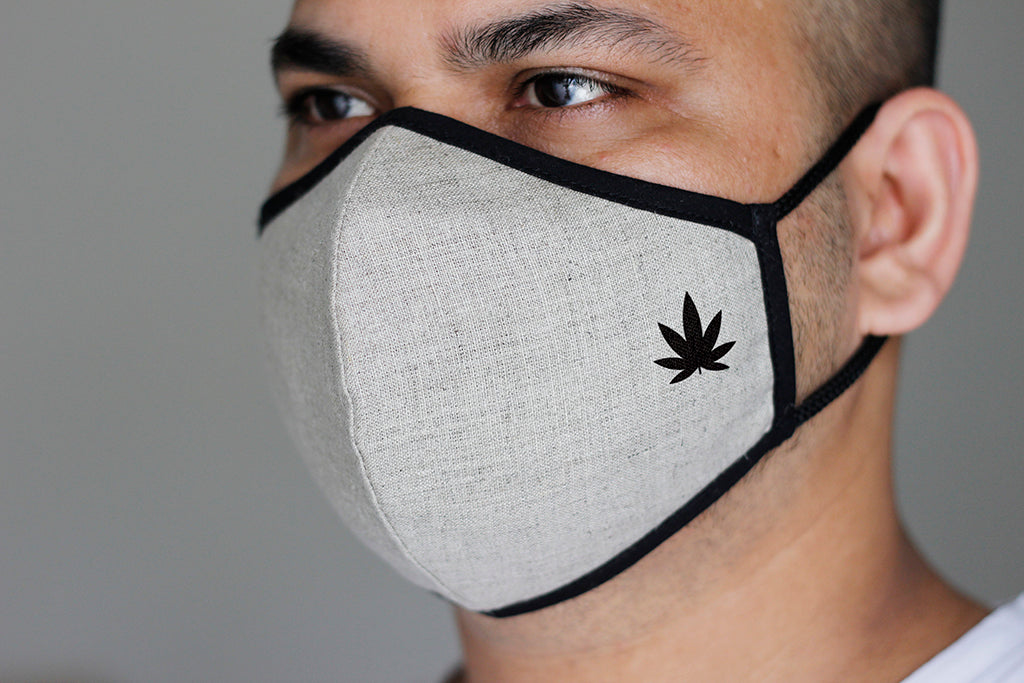 Close-up of man wearing white organic hemp fabric face mask with black trim and leaf logo, side profile fit view