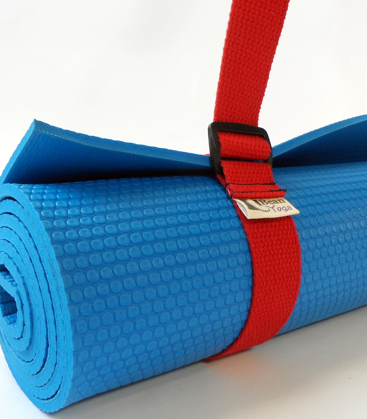 Blue yoga mat rolled and fastened with red cotton sling strap for compact carrying