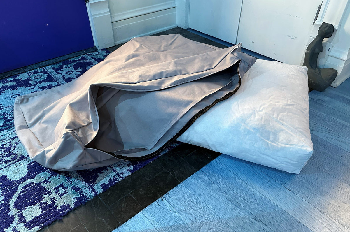 Dog bed with gray cover opened to show white foam cushion insert