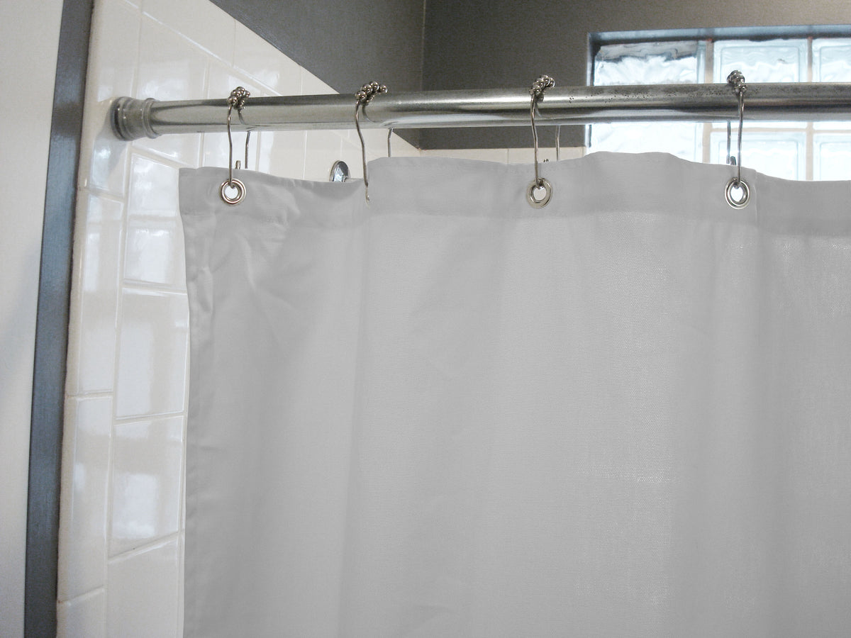 White cotton shower curtain hanging in modern bathroom with chrome rod